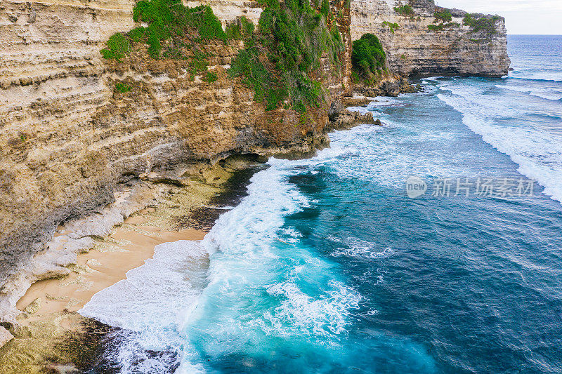 Uluwatu巴厘岛。蓝色的海洋和岩石山，覆盖着热带树木。