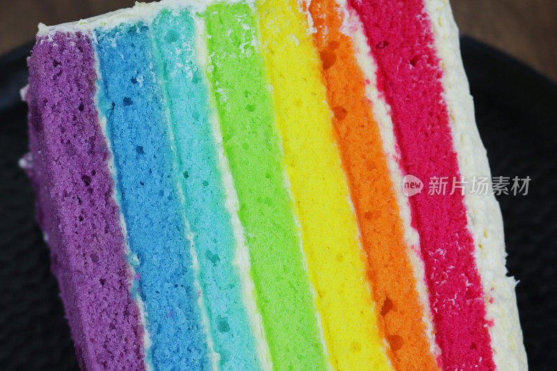 彩虹蛋糕的切片图像显示了多色海绵层与奶油糖霜的照片