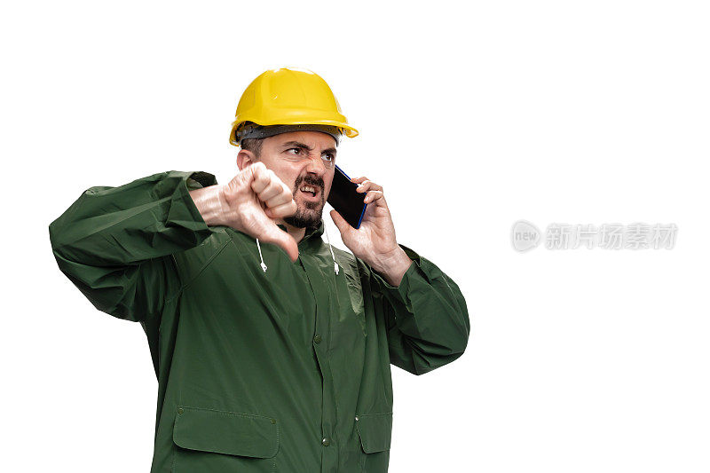 身穿绿色雨衣、头戴安全帽的工程师使用智能手机，在白色背景上显示“拇指向下”的标识