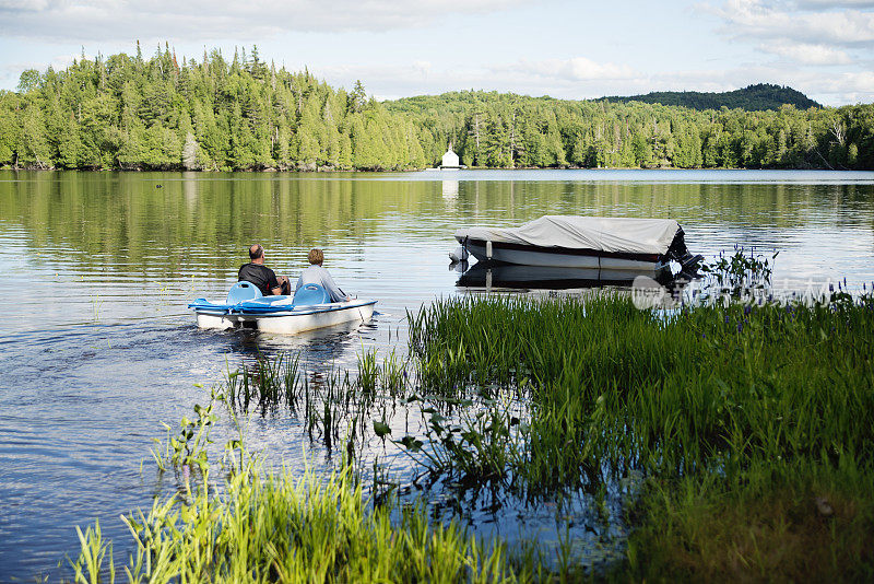 老人和成年侄女在乡村湖上的脚踏船上。