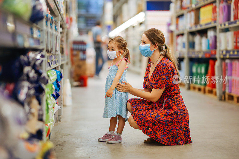 带着女儿戴着防护面具购物的女人