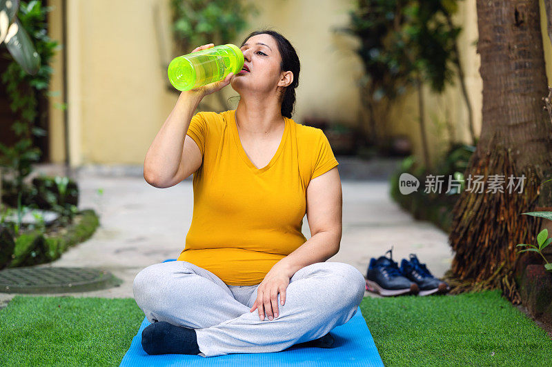 女人在做晨练和瑜伽的时候喝水。