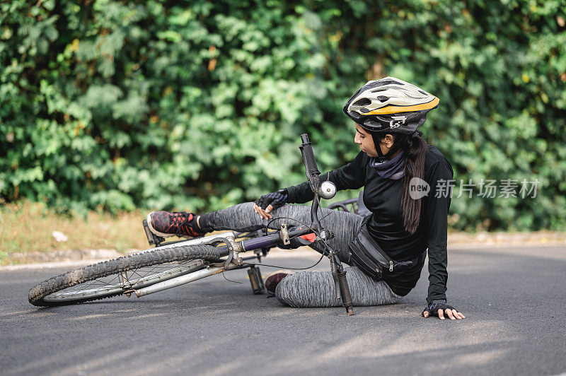 自行车受伤，女运动员从自行车上摔在路上。