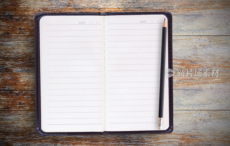 空白纸笔记本或记事本和铅笔在棕色木制桌子的背景。