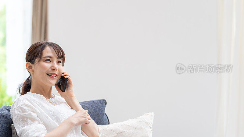 迷人的日本女人在客厅使用智能手机