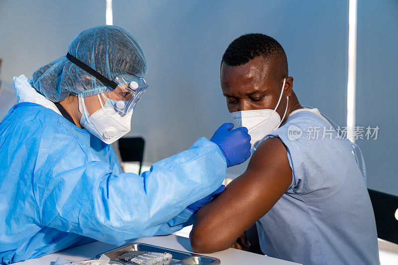 一名医生用注射器为非裔美国人注射新冠肺炎疫苗，防止新冠肺炎疫情爆发