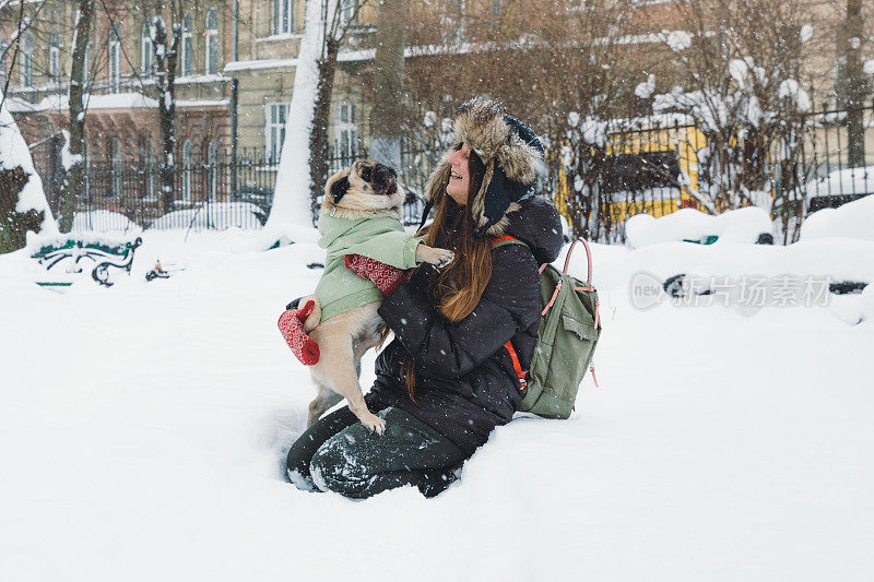 快乐的年轻女子背包享受第一雪在公园散步与小可爱的狗