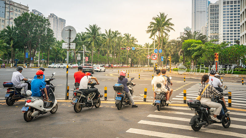 在中国海南现代海口的街道上，人们骑着摩托车
