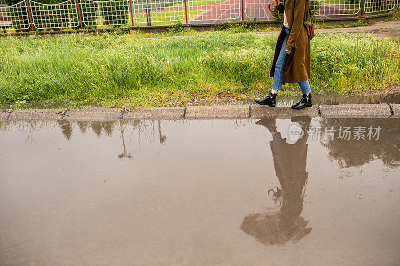 侧视图，不认识的女人走在路边在雨天