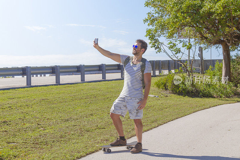 美国佛罗里达州基韦斯特，一个炎热阳光明媚的夏日，一名年轻人正在用智能手机自拍