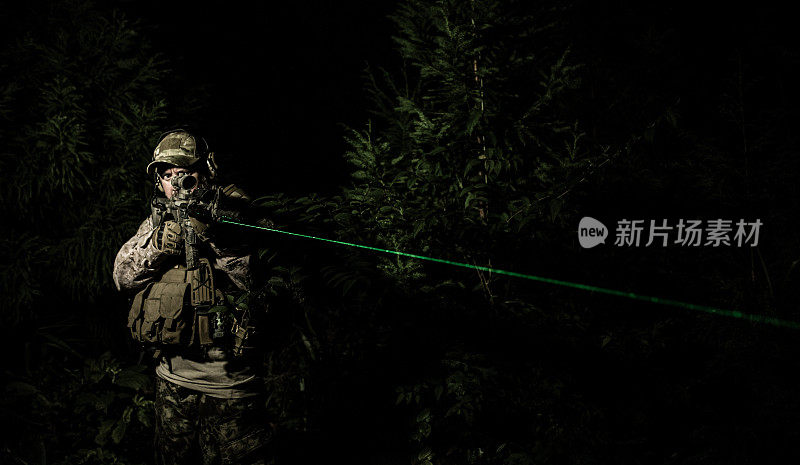 夜间军事特殊行动操作员正在用绿色激光瞄准步枪