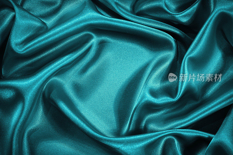 美丽的蓝绿丝缎背景。波浪柔软的褶皱。豪华的丝绸织物背景与空间的产品和设计。网页横幅。