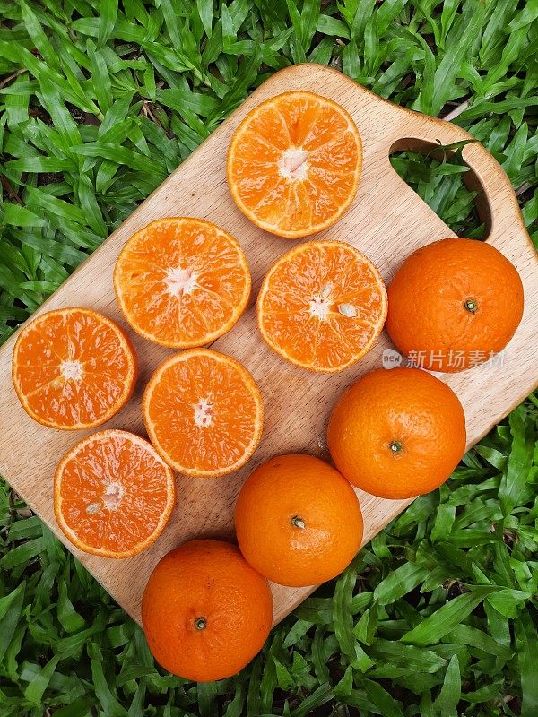 切菜板上的橙色水果-草地背景。