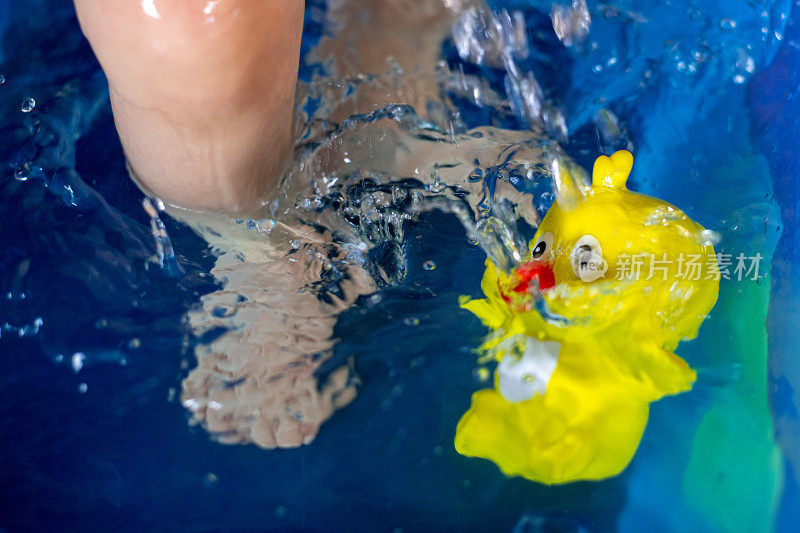 孩子在水里，带着黄色的小鸡(橡胶玩具)。