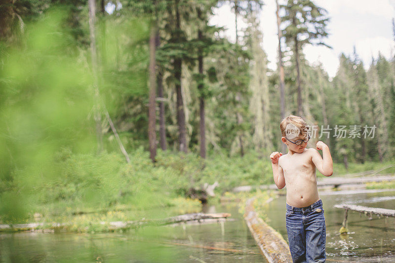 小男孩在森林溪流上的原木肖像