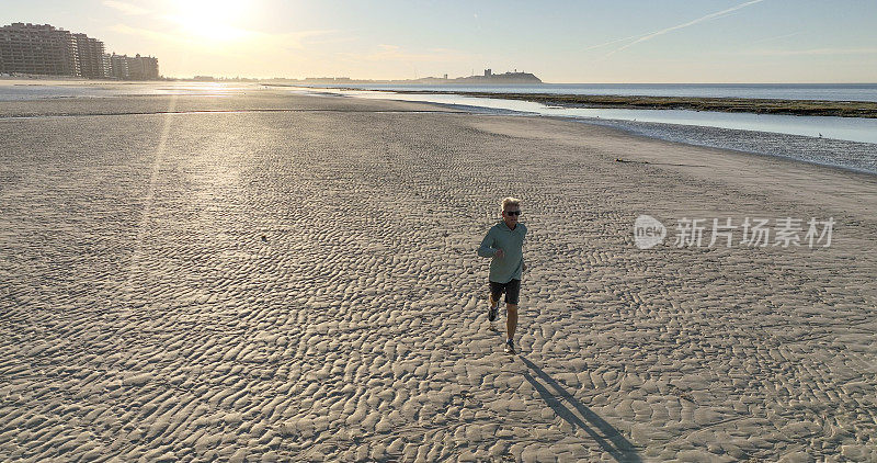 鸟瞰图，男子奔跑在空旷的海滩上