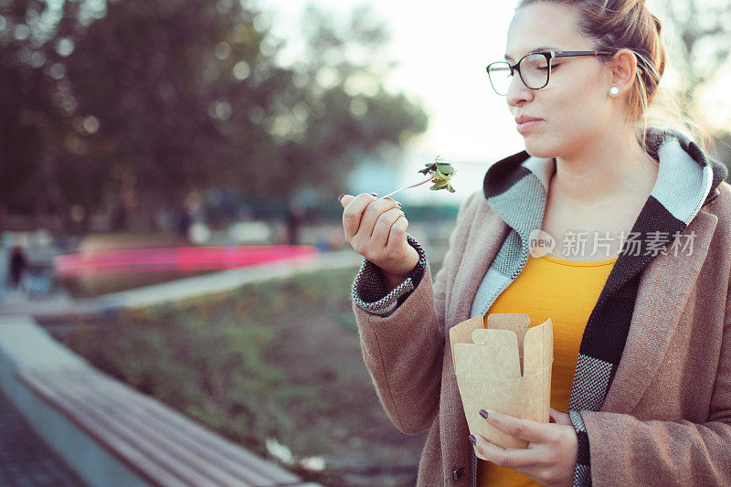 一个年轻的女人在公园里吃午饭。