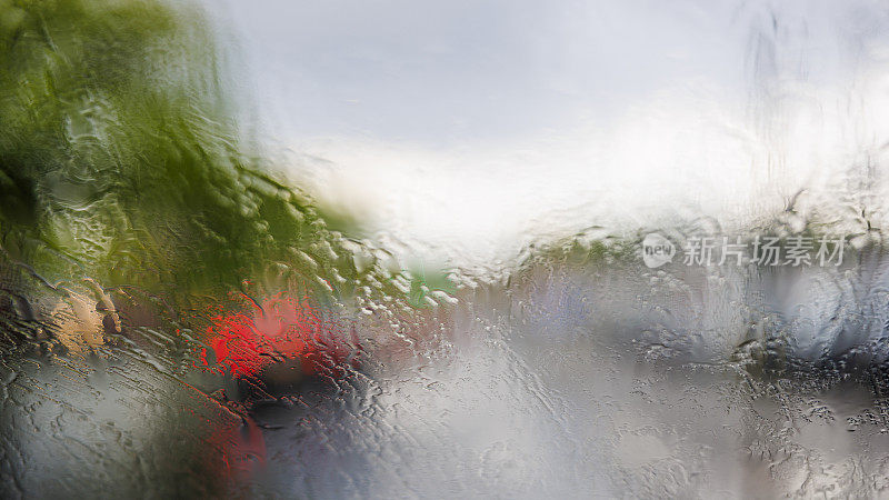 在倾盆大雨中行驶在纽约皇后大道上。从驾驶室看到的挡风玻璃上的风景。街道因为水的影响而变得模糊和扭曲。