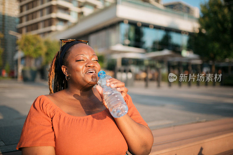 快乐的年轻成年女性喝瓶装水