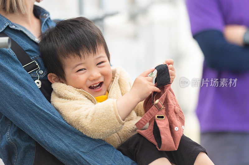 快乐的小男孩被妈妈抱着