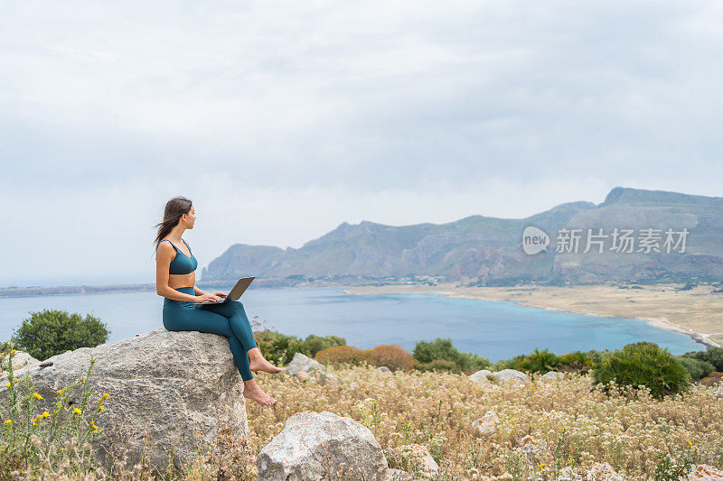 年轻女子在笔记本电脑上工作，在沿海的观点