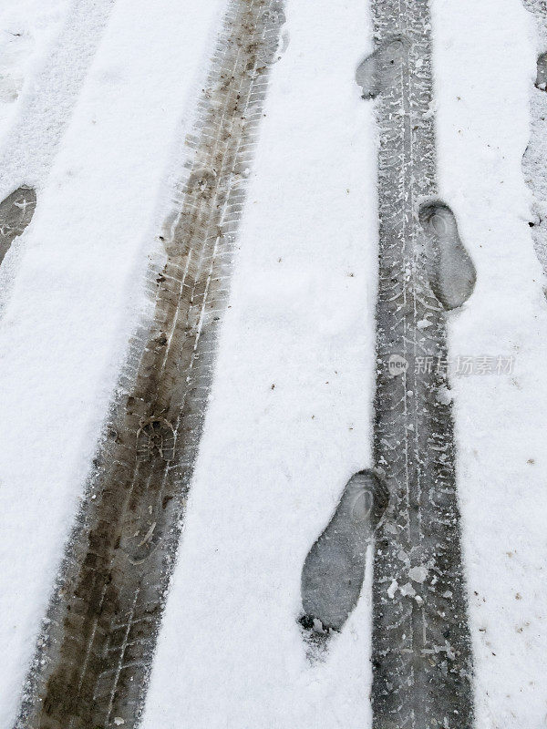 雪地里有轮胎印和人类脚印。