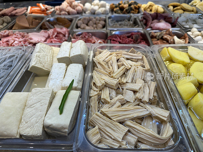 农产品市场货架上的全画幅图像，展示了成堆的新鲜和准备好的水果和蔬菜，包括去皮的土豆和蘑菇，豆腐块，塑料托盘里的章鱼触手，杂货区，高架视图