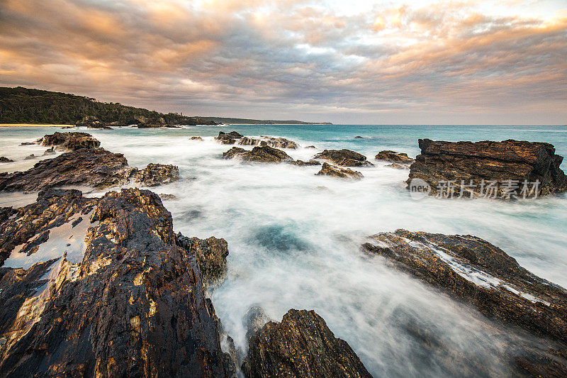 海浪轻轻拍打岩石的海景，以及引人注目的云景