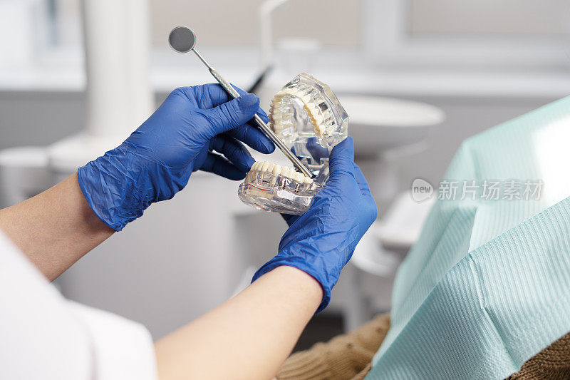 牙医在牙科诊所工作，与病人沟通。牙医展示下颚，展示如何用牙科器械进行牙科治疗。