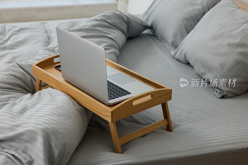 室内床上的木制托盘桌和笔记本电脑
