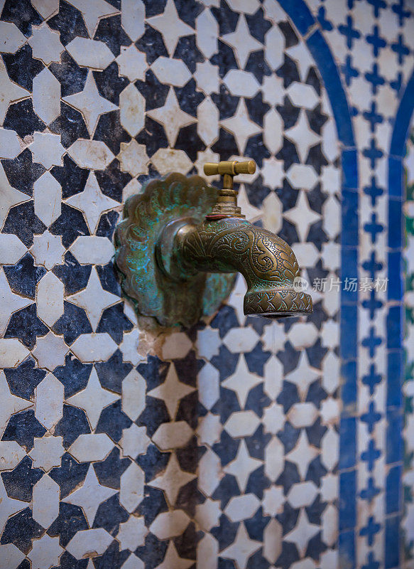 摩洛哥非斯的街道上，一个贴着瓷砖的铜水龙头。