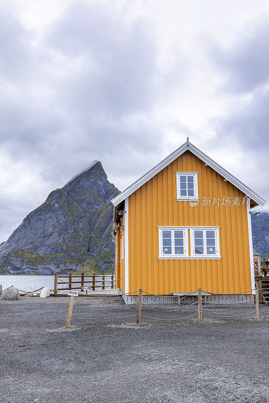 位于挪威罗弗敦群岛上的一个小渔村Sakrisøy的黄色钓鱼小屋，背景是一座山