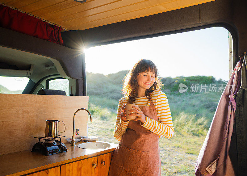 穿围裙的女人在露营车里喝咖啡