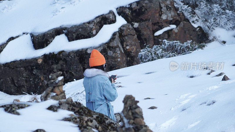 一个女人在寒冷的天气里穿行于白雪覆盖的山林之中