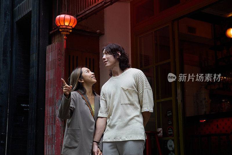 一对亚洲夫妇牵着手走过香港街头，彼此凝视着对方的眼睛。