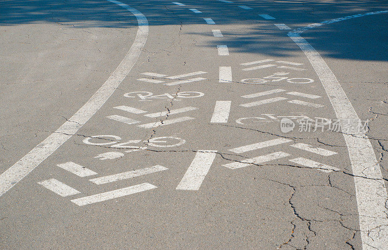 双向自行车道。柏油路上有白色带箭头的自行车标志，街道上有自行车路标志。柏油路上的道路标记。