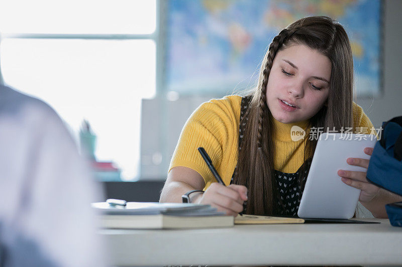 十多岁的女孩在教室里用平板电脑做笔记