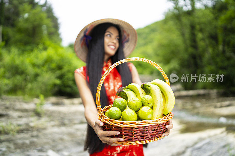 美丽的中国女人拿着一个装满香蕉和酸橙的篮子