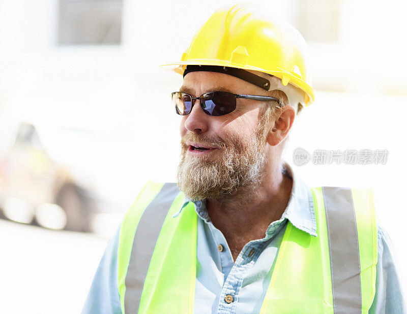 成熟的建筑工人戴着安全帽和太阳镜微笑着
