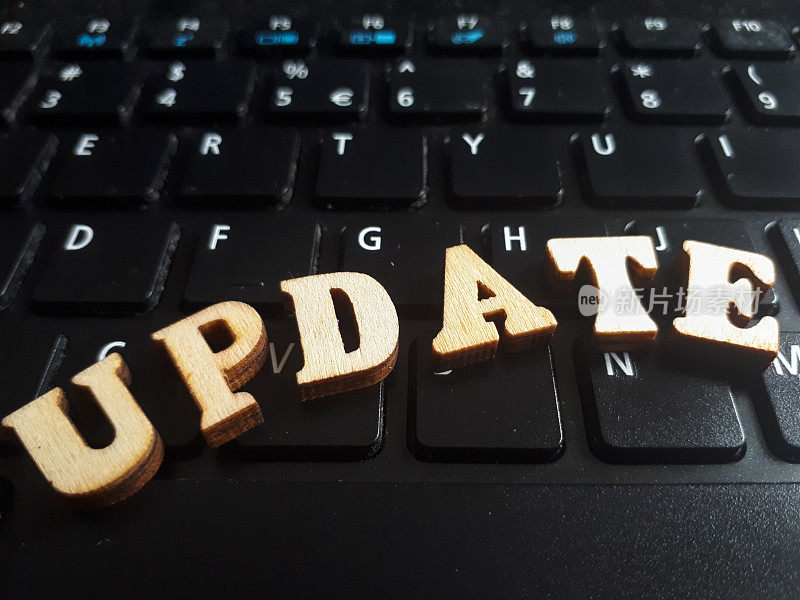 “update”这个词是由木制字母组成的。键盘背景木铭文