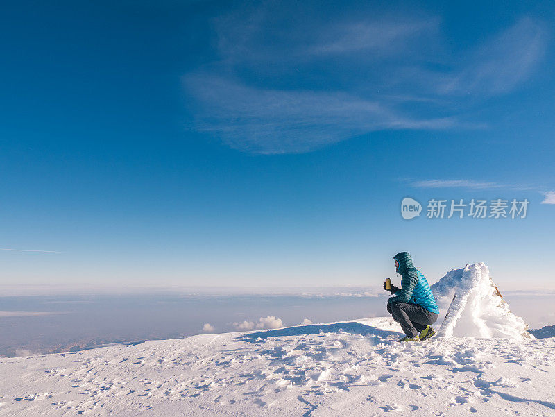 冬季日出时，高山攀登者在高海拔的山峰上喝咖啡