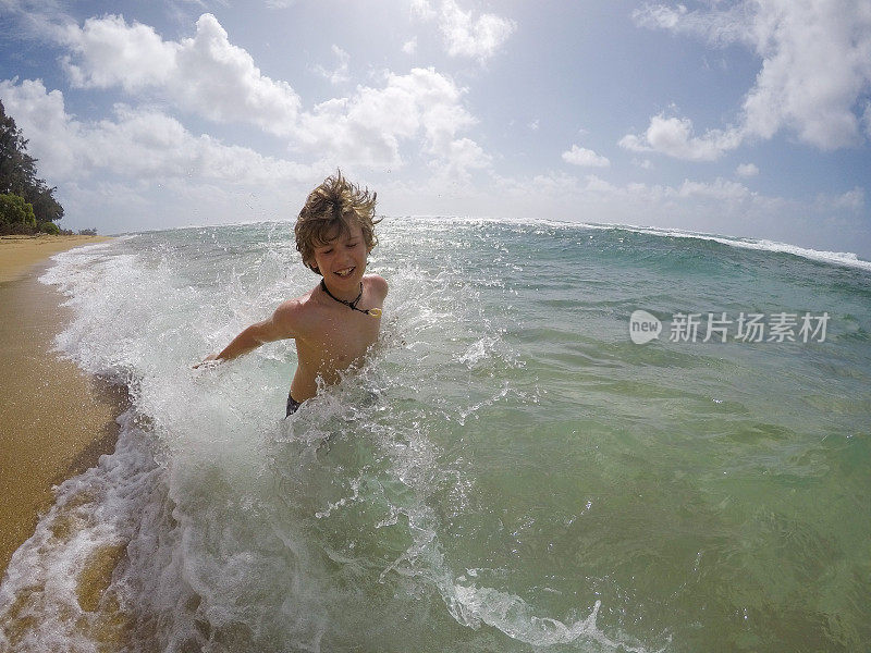 小男孩在夏威夷考艾岛玩，溅水，享受美丽的海水。