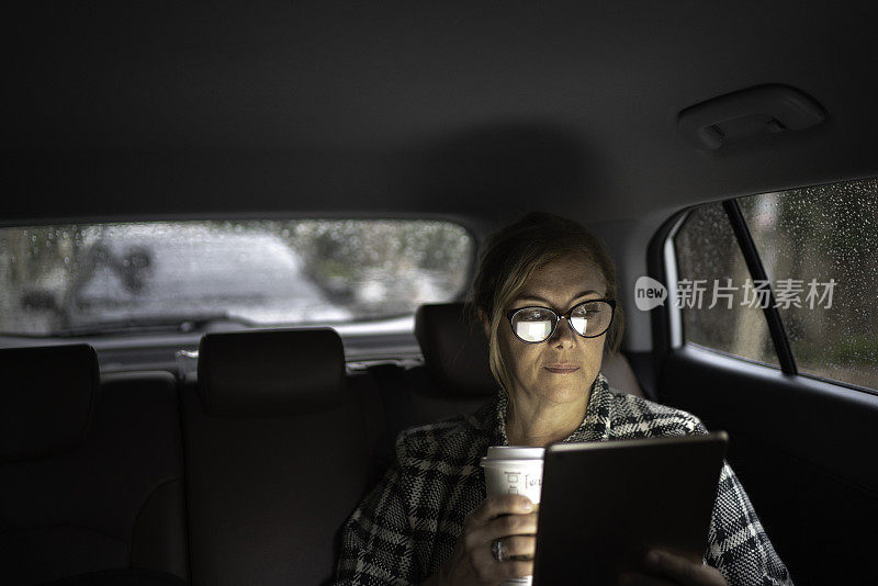 在出租车里工作的女人，用着平板电脑，喝着咖啡