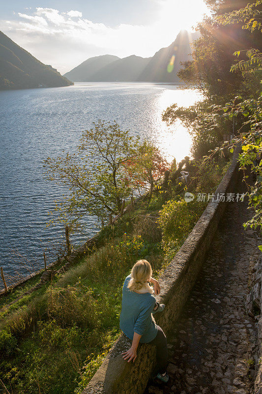 日出时，一个女人停在湖边的小路上