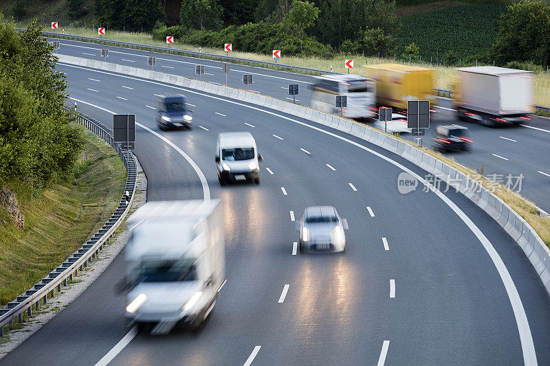 半卡车和汽车在高速公路上在黄昏时超速行驶，重型货物运输在德国