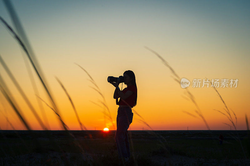 摄影师女孩用单反相机拍摄日落