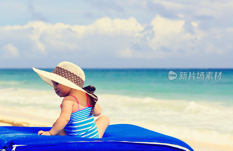 可爱的小女孩戴着大帽子在夏天的海滩上