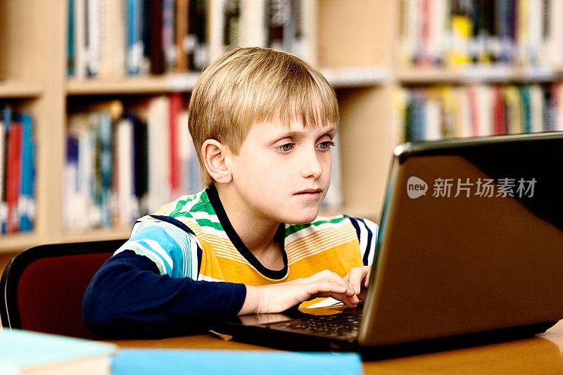 图书馆里的金发小男孩被笔记本电脑迷住了