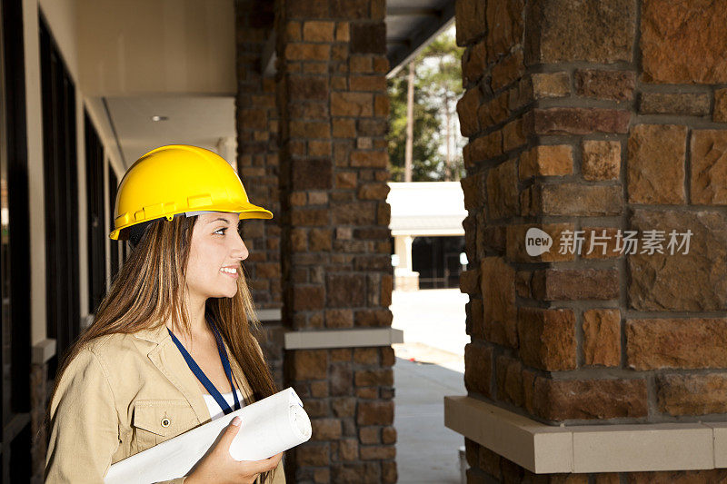 女建筑师持有蓝图，计划在商业建筑工地。