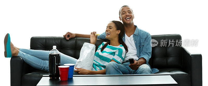 幸福的年轻夫妇在沙发上吃东西
